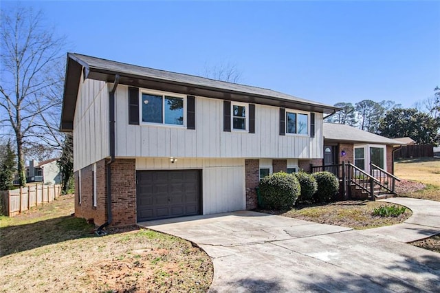 tri-level home featuring brick siding, concrete driveway, an attached garage, and fence