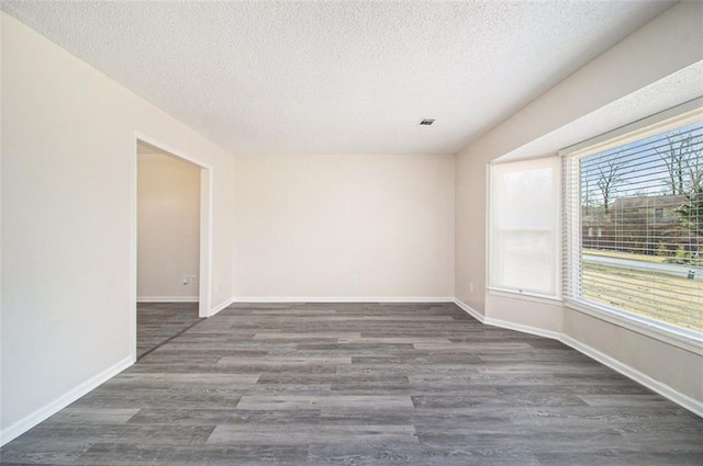 spare room with baseboards, a textured ceiling, and wood finished floors