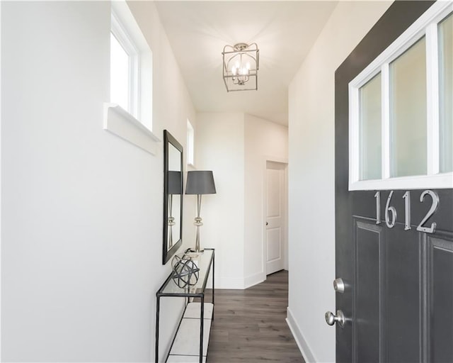 hall with dark hardwood / wood-style floors and an inviting chandelier