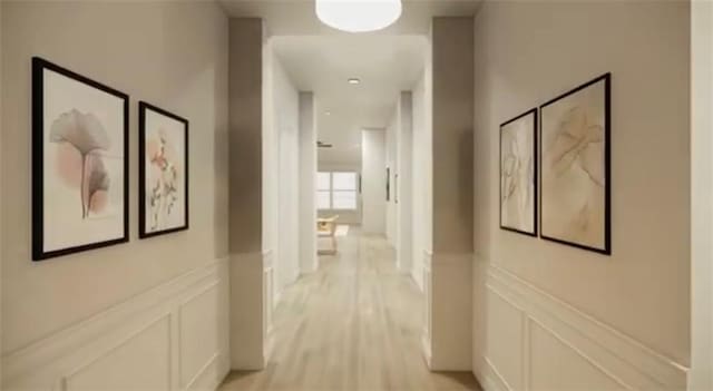 hallway with a decorative wall, a wainscoted wall, and light wood-style floors