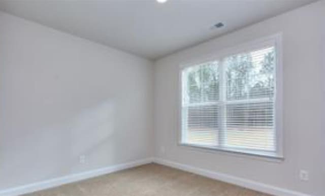 empty room featuring baseboards and light colored carpet