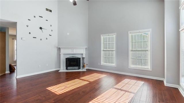 unfurnished living room featuring a towering ceiling and dark hardwood / wood-style flooring