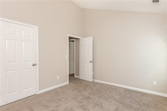 unfurnished bedroom featuring light colored carpet, high vaulted ceiling, and a closet