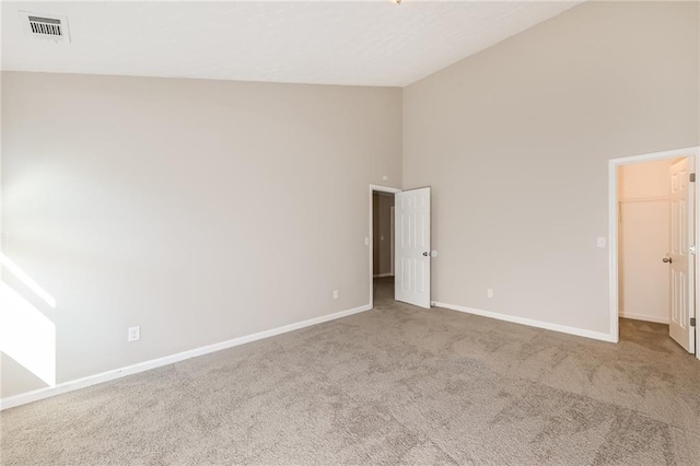 empty room featuring light colored carpet and high vaulted ceiling