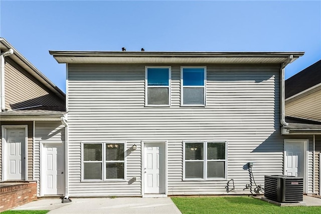 rear view of property with cooling unit and a yard