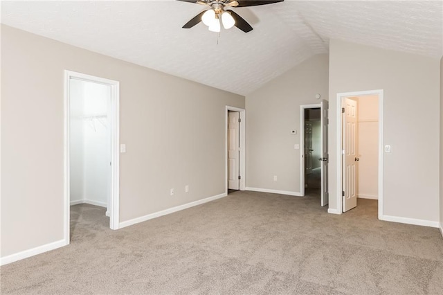 unfurnished bedroom with light carpet, a walk in closet, a closet, and ceiling fan