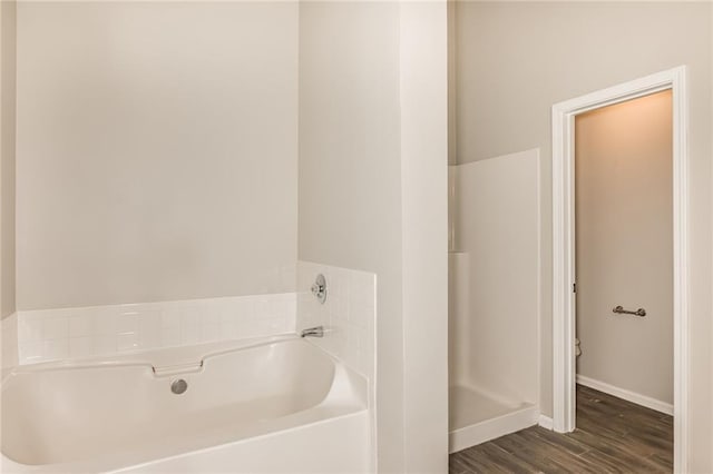 bathroom with hardwood / wood-style floors and a tub to relax in