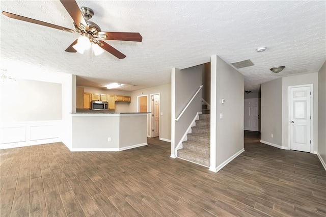 unfurnished living room featuring a textured ceiling, dark hardwood / wood-style flooring, and ceiling fan