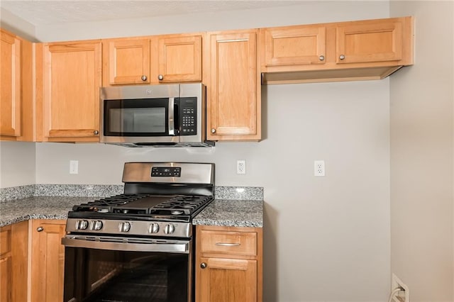 kitchen with stone counters, light brown cabinets, and stainless steel appliances