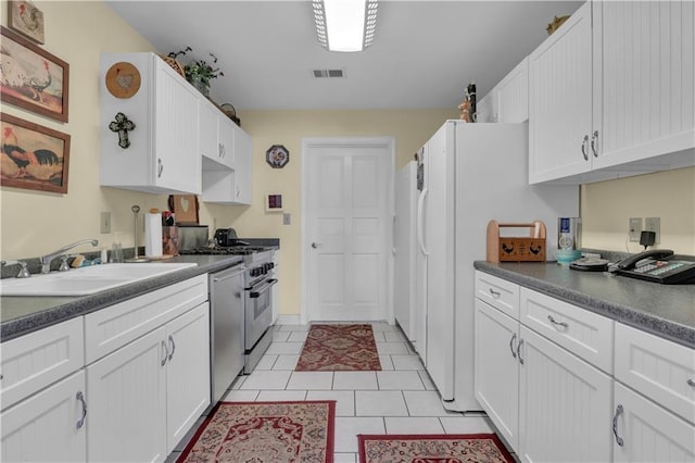 14501 Woolsey Rd, Hampton, GA 30228 - kitchen with white cabinets, dark countertops, stainless steel appliances, and light tile patterned flooring
