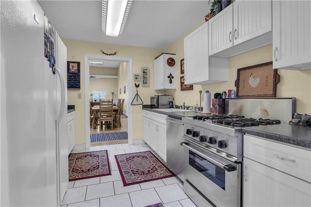 14501 Woolsey Rd, Hampton, GA 30228 - kitchen featuring stainless steel appliances, white cabinets, dark countertops, and light tile patterned floors