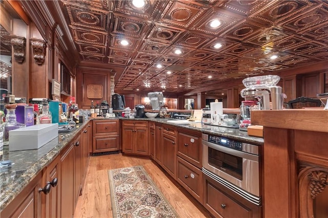 14501 Woolsey Rd, Hampton, GA 30228 - kitchen featuring oven, brown cabinets, an ornate ceiling, light wood-type flooring, and dark stone countertops