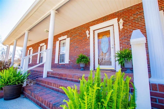 property entrance with a porch and brick siding