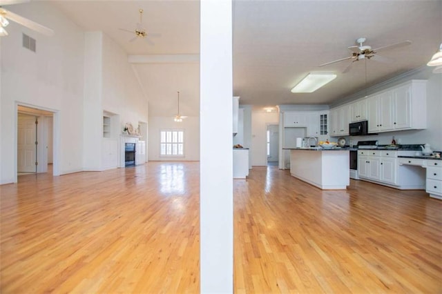 kitchen featuring stove, open floor plan, ceiling fan, dark countertops, and high vaulted ceiling