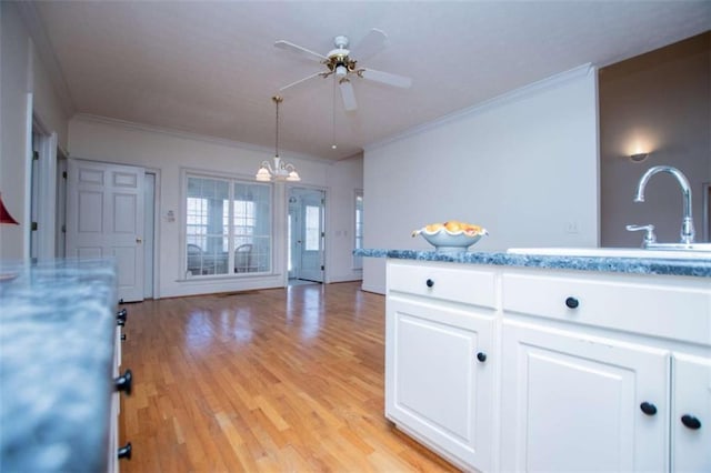 kitchen with a sink, a ceiling fan, white cabinetry, light wood-type flooring, and crown molding
