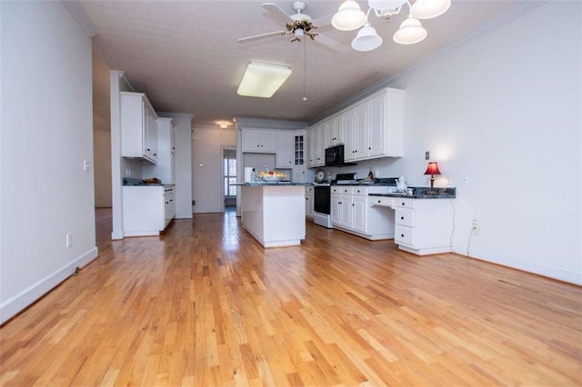 kitchen with gas range, dark countertops, light wood-type flooring, black microwave, and crown molding
