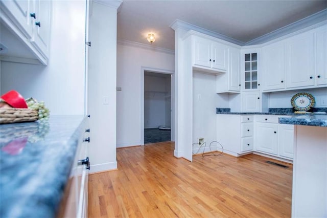 kitchen with white cabinetry, light wood-type flooring, crown molding, glass insert cabinets, and baseboards