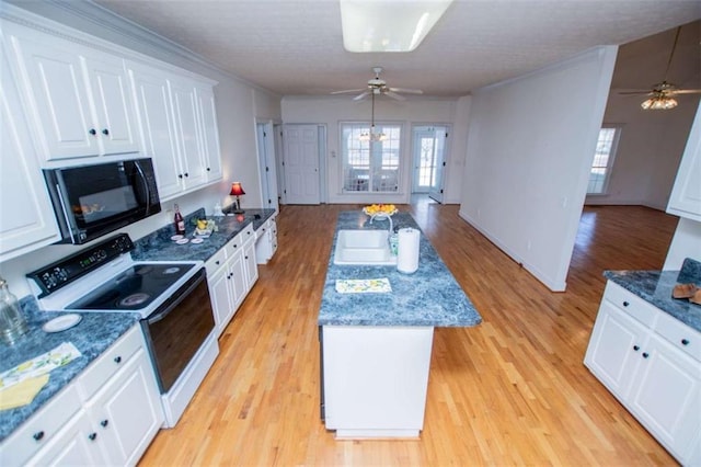 kitchen featuring electric range, black microwave, a ceiling fan, a sink, and white cabinetry