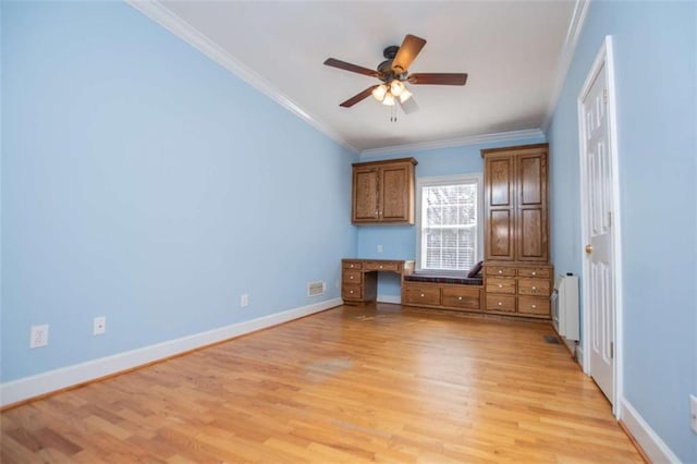 spare room with light wood-type flooring, ceiling fan, ornamental molding, baseboards, and radiator heating unit