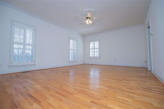 empty room with ornamental molding, light wood-type flooring, a ceiling fan, and baseboards