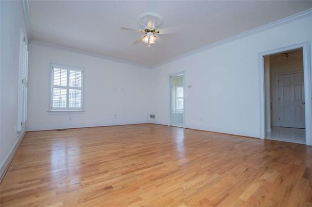 spare room featuring ornamental molding, ceiling fan, light wood-type flooring, and baseboards