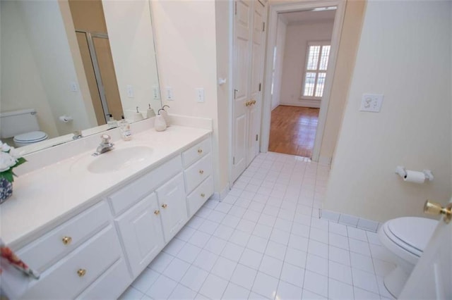 full bath featuring toilet, tile patterned flooring, vanity, and a shower with door