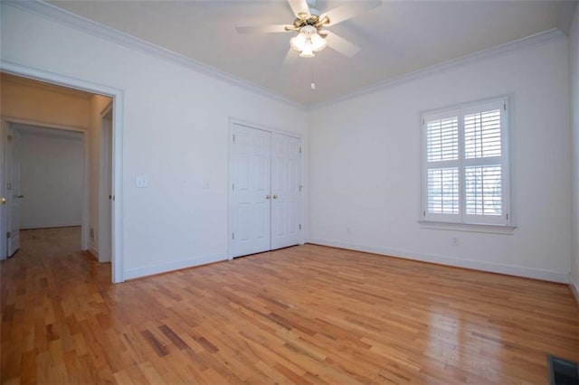 unfurnished bedroom featuring ornamental molding, light wood-style floors, baseboards, a ceiling fan, and a closet