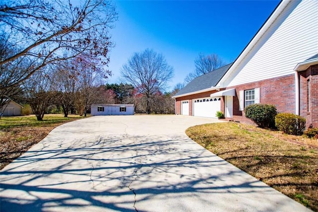 view of home's exterior featuring driveway, brick siding, and an attached garage