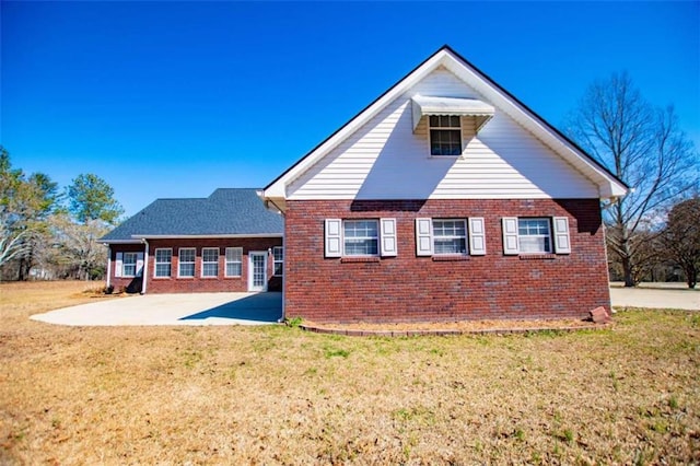 back of property with brick siding, a patio, and a yard