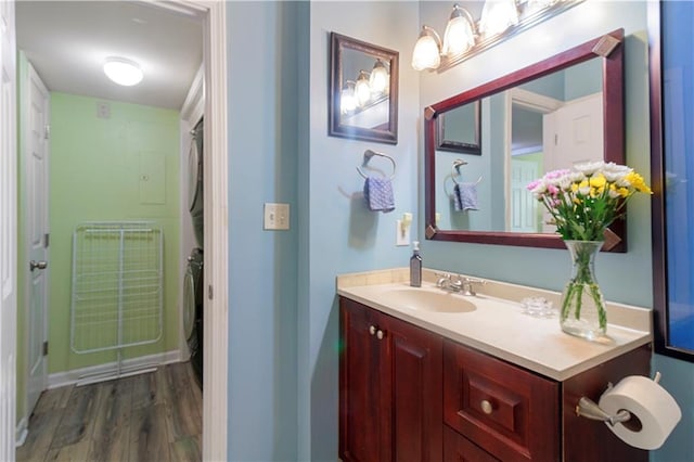 bathroom featuring vanity, stacked washer and dryer, baseboards, and wood finished floors