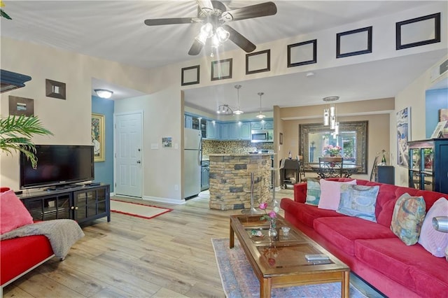 living area with baseboards, a ceiling fan, and light wood finished floors
