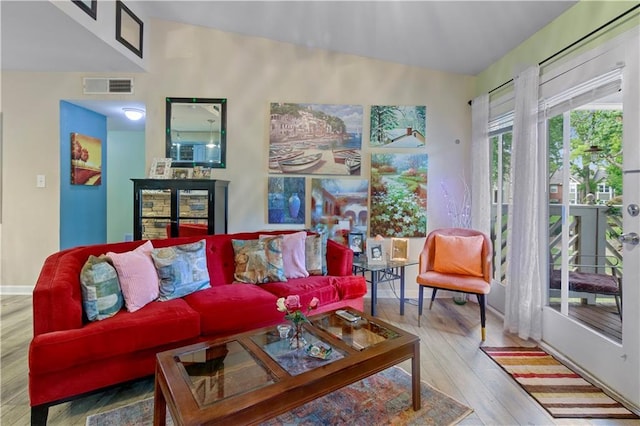 living area with baseboards, visible vents, wood finished floors, and lofted ceiling