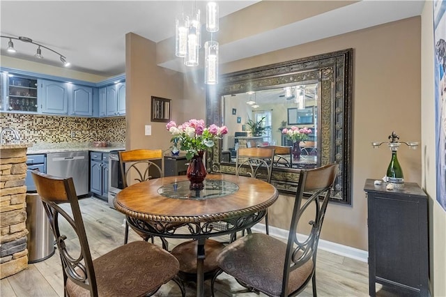 dining room featuring baseboards, rail lighting, and light wood-style flooring