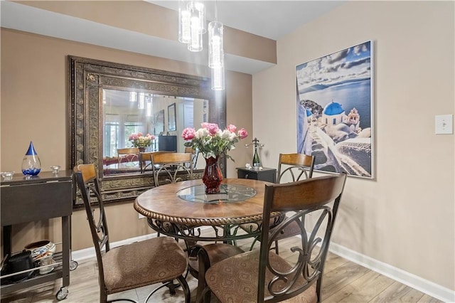 dining space featuring light wood-type flooring and baseboards