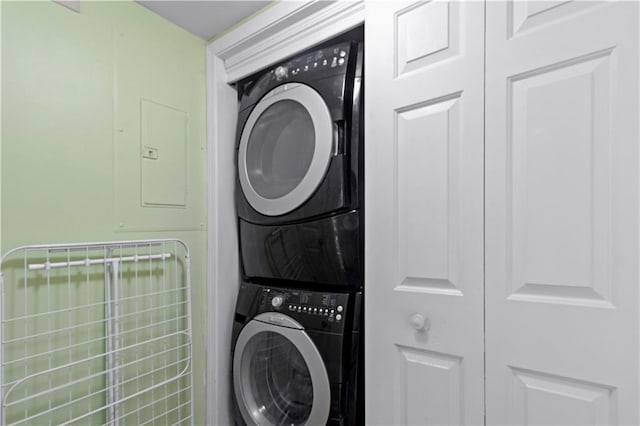 clothes washing area featuring laundry area, stacked washing maching and dryer, and electric panel