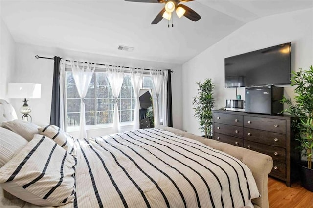 bedroom with light hardwood / wood-style flooring, vaulted ceiling, and ceiling fan