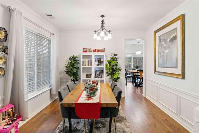 dining area featuring a notable chandelier, plenty of natural light, dark hardwood / wood-style flooring, and crown molding