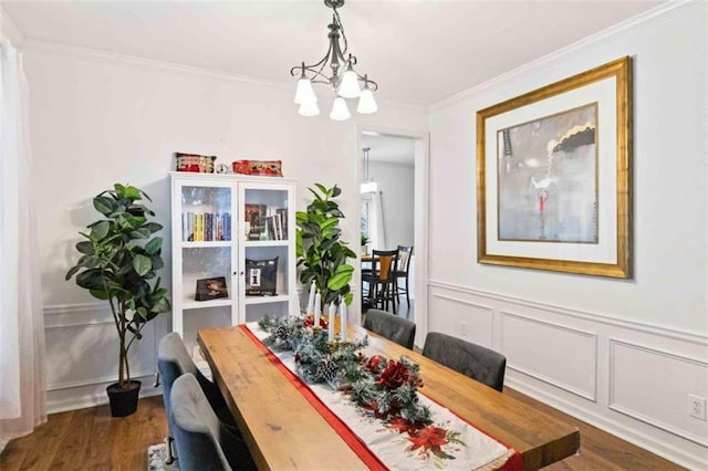 dining room with crown molding, dark wood-type flooring, and an inviting chandelier