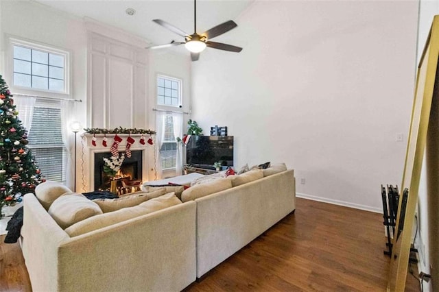 living room featuring ceiling fan, dark hardwood / wood-style flooring, and a fireplace