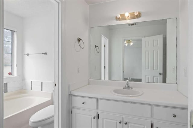 bathroom featuring vanity, toilet, and a tub