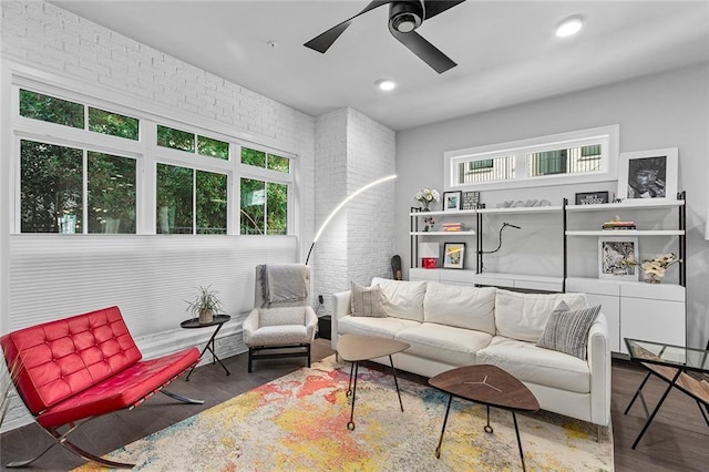 living area with a ceiling fan, recessed lighting, wood finished floors, and brick wall