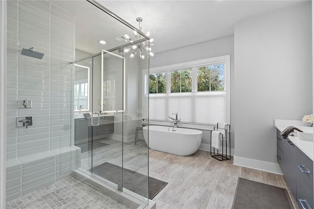 bathroom with a stall shower, wood finished floors, baseboards, a soaking tub, and vanity