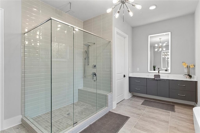 bathroom with a chandelier, a shower stall, vanity, and baseboards