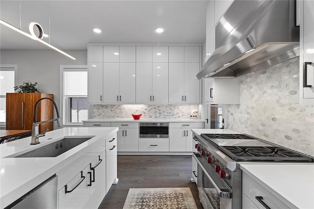 kitchen with a sink, light countertops, wall chimney exhaust hood, and stainless steel appliances