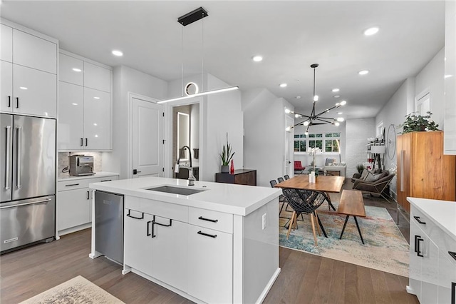 kitchen with a sink, dark wood finished floors, light countertops, stainless steel appliances, and modern cabinets