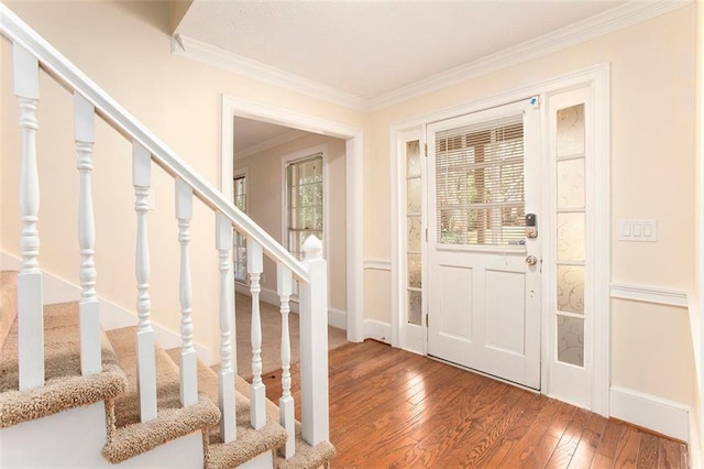 foyer entrance with crown molding, stairway, baseboards, and wood finished floors