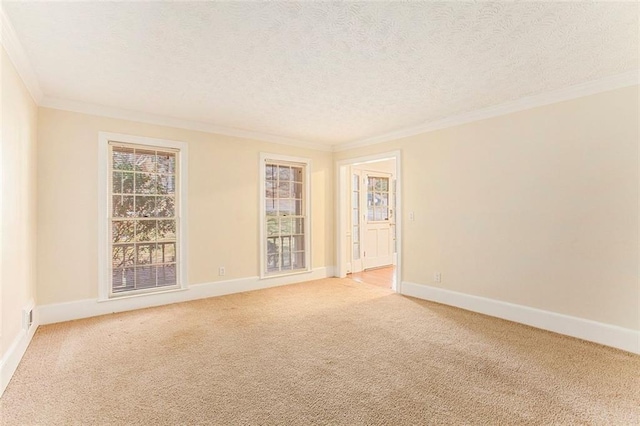 empty room featuring ornamental molding, light colored carpet, a textured ceiling, and baseboards