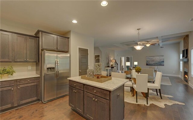 kitchen with a center island, stainless steel fridge, dark hardwood / wood-style flooring, and light stone countertops