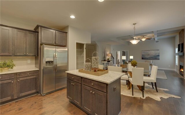 kitchen with dark hardwood / wood-style floors, a center island, light stone countertops, and stainless steel fridge with ice dispenser