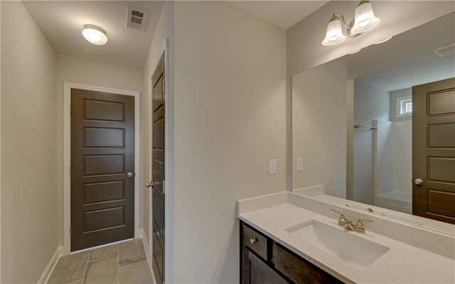 bathroom with a shower, vanity, and tile patterned floors